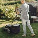 man-cutting-grass-with-lawn-mover-in-the-back-yard-male-in-a-shirt(1)